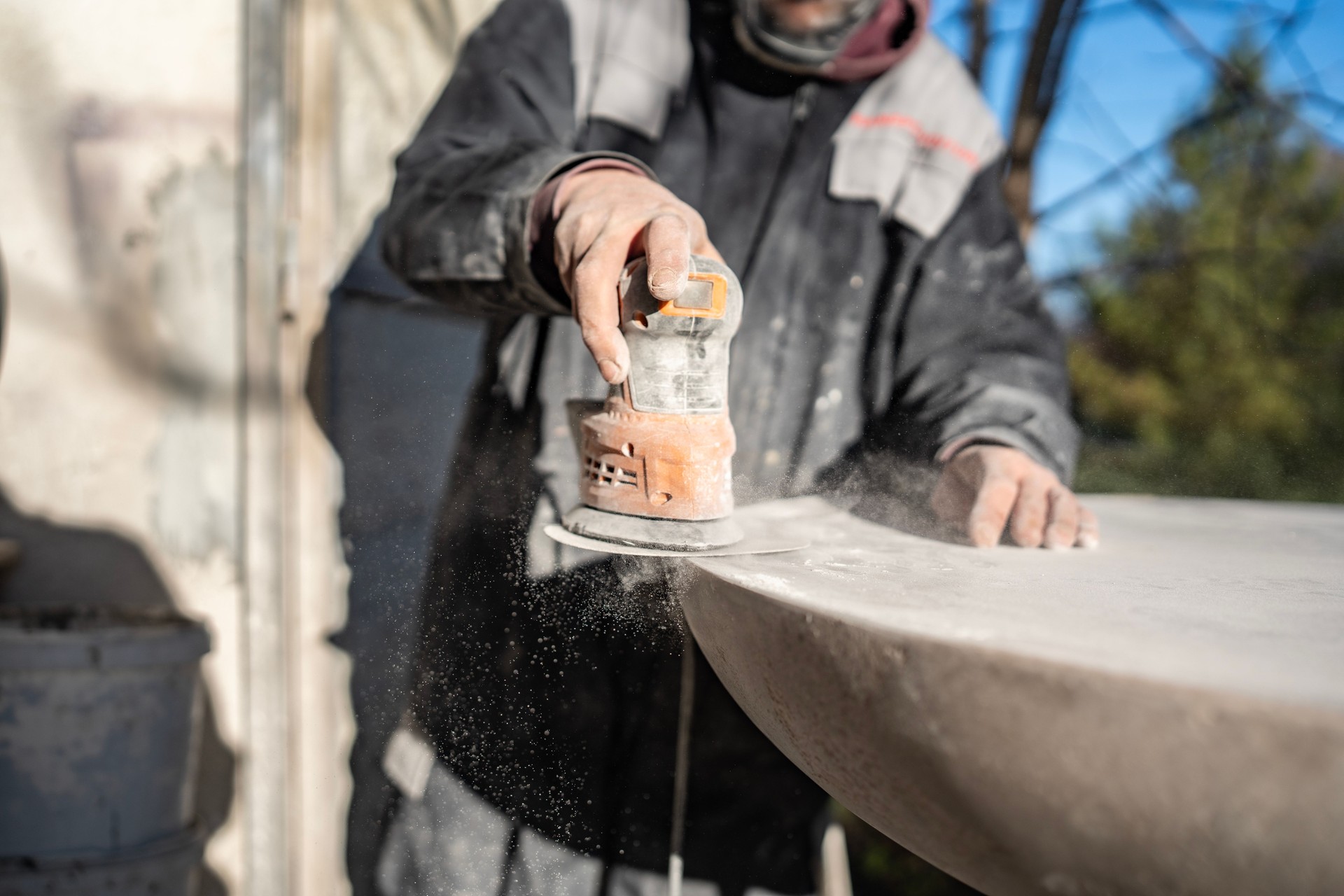 Worker Using an Electric Sander on a Large Stone Surface Outdoors