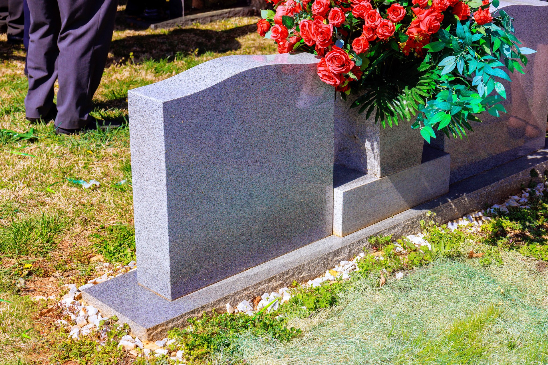 Flowers placed at gravestone during memorial service in serene cemetery setting