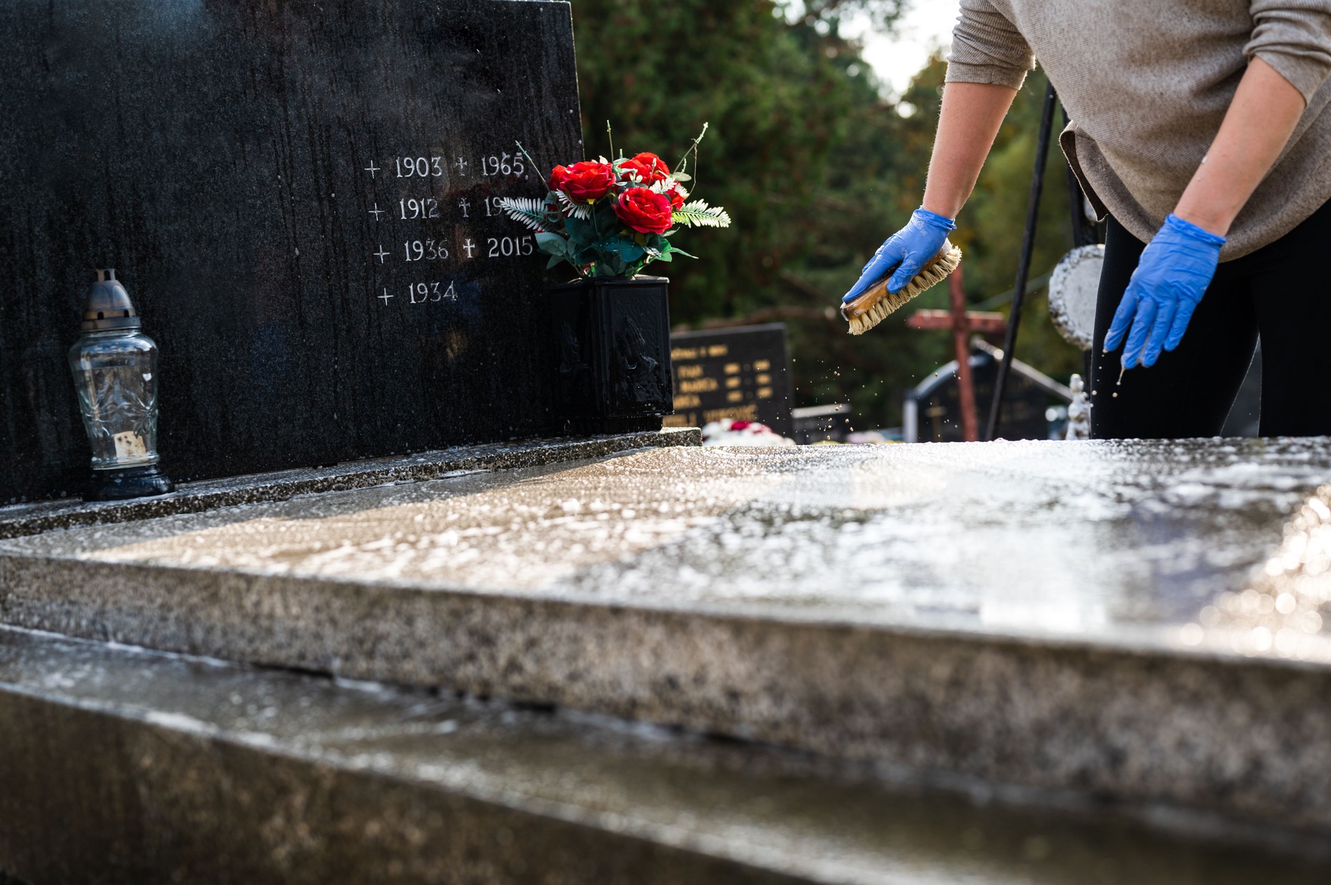 Woman washing tombstone with a brush